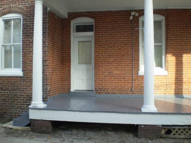 A porch with a white door and two white columns.