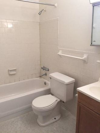 a white bathroom with a toilet and a bath tub
