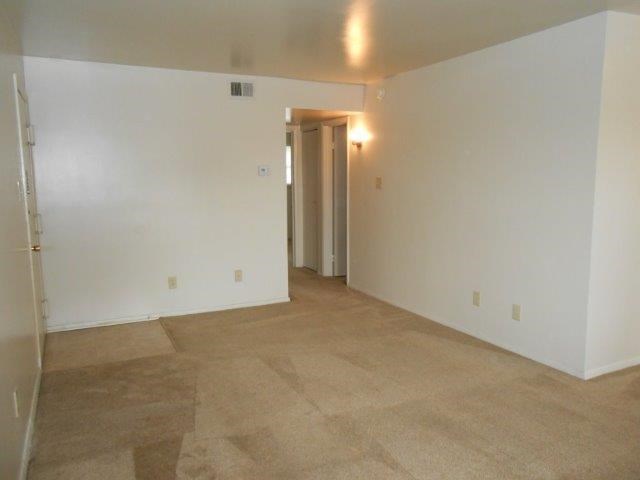 an empty living room with white walls and tile floor