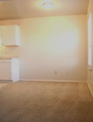 an empty living room and kitchen with a white wall