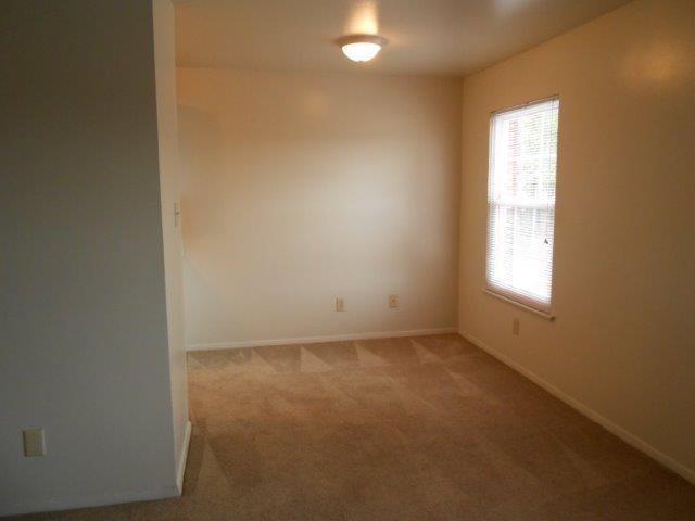 an empty living room with a window and carpet