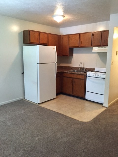 an empty kitchen with a white refrigerator and stove