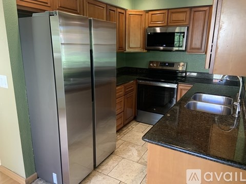 A kitchen with a stainless steel refrigerator and a black stove top oven.