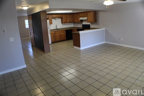 A kitchen with brown cabinets and a black refrigerator.