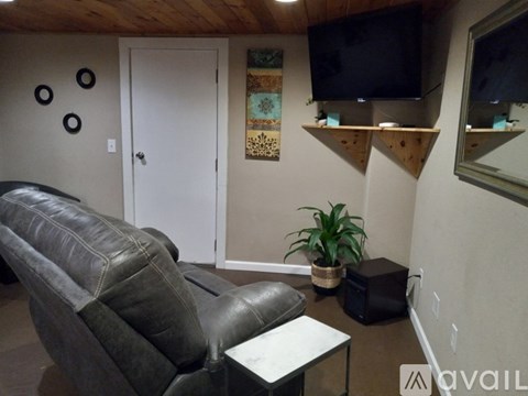 A living room with a grey couch and a flat screen TV mounted on the wall.