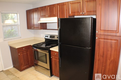 A kitchen with wooden cabinets and a black refrigerator.