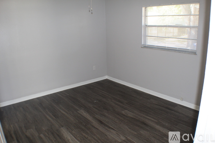 A room with wooden flooring and a window with blinds.