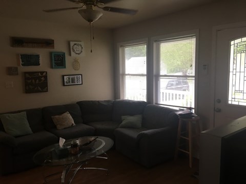 A living room with a black couch and a glass coffee table.