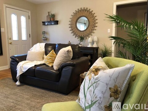 A living room with a black couch and a green armchair.