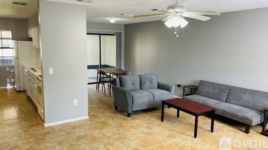 A living room with a grey couch, a black coffee table, and a ceiling fan.