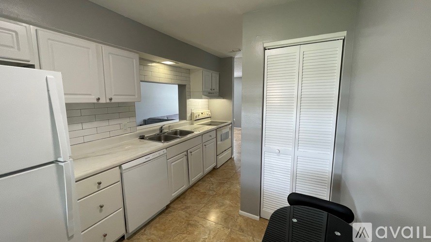 A kitchen with white cabinets and a black chair.