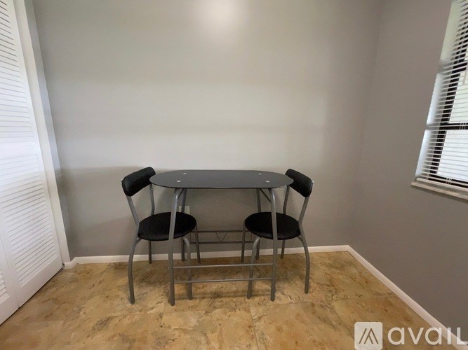 A table with two chairs is in a room with a tan floor.