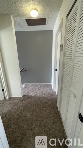 A hallway with a carpeted floor and white walls.