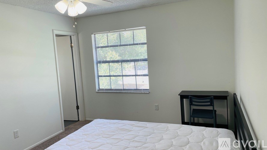 A bedroom with a bed, desk, and window.