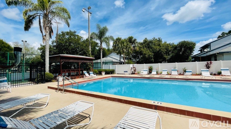 A pool surrounded by sun loungers and palm trees.