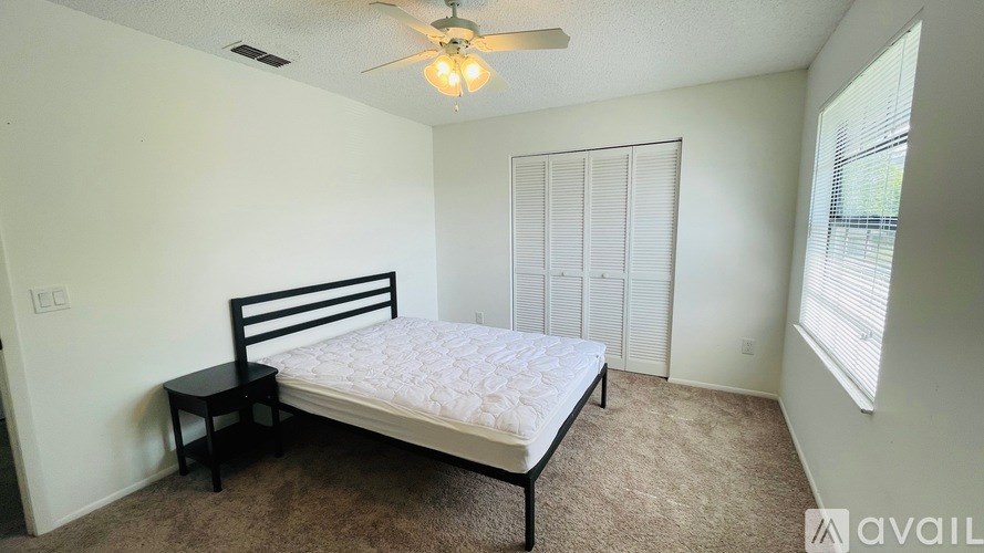 A bedroom with a bed, a chair, and a ceiling fan.