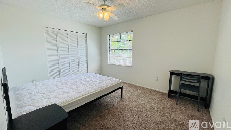A bedroom with a bed, desk, and window.