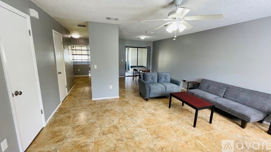 A living room with a grey couch, a coffee table, and a ceiling fan.