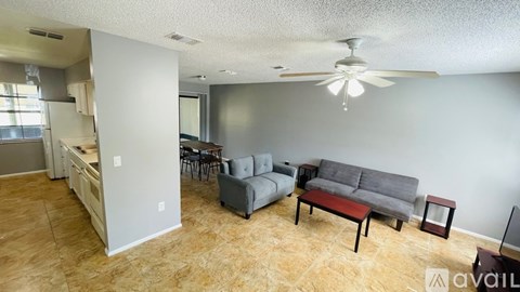 A living room with a grey couch and a fan on the ceiling.