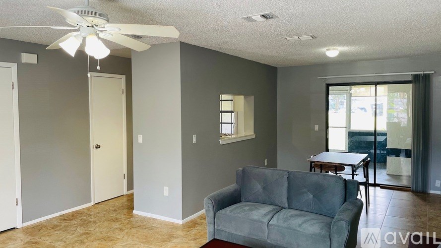A living room with a grey couch and a ceiling fan.
