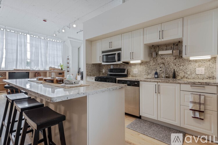 A kitchen with white cabinets and a marble countertop.