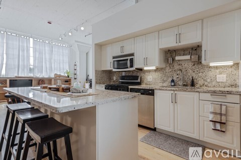 A kitchen with white cabinets and a marble countertop.