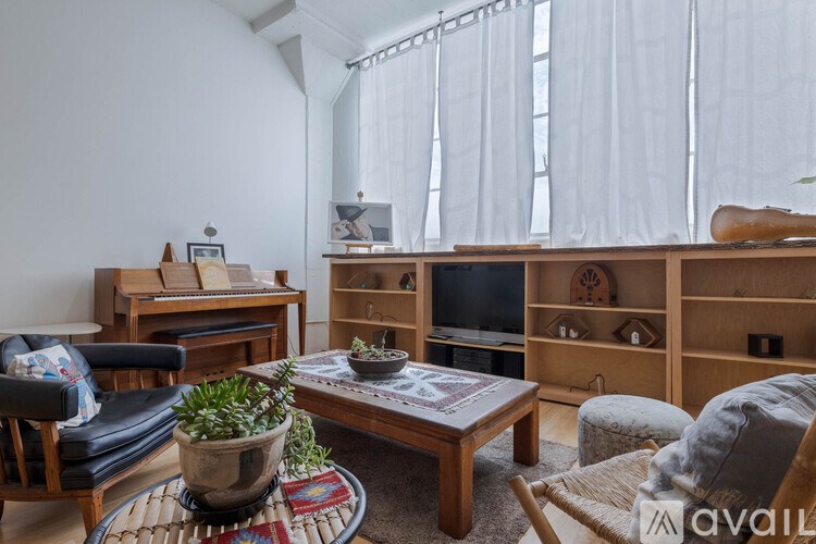 A living room with a black leather chair, a wooden coffee table, and a wooden bookshelf.