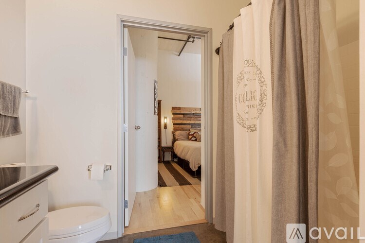 A bathroom with a toilet, sink, and a bedroom in the background.