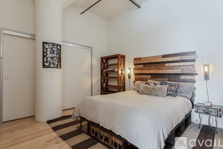 A bedroom with a bed, a wooden headboard, and a rug.