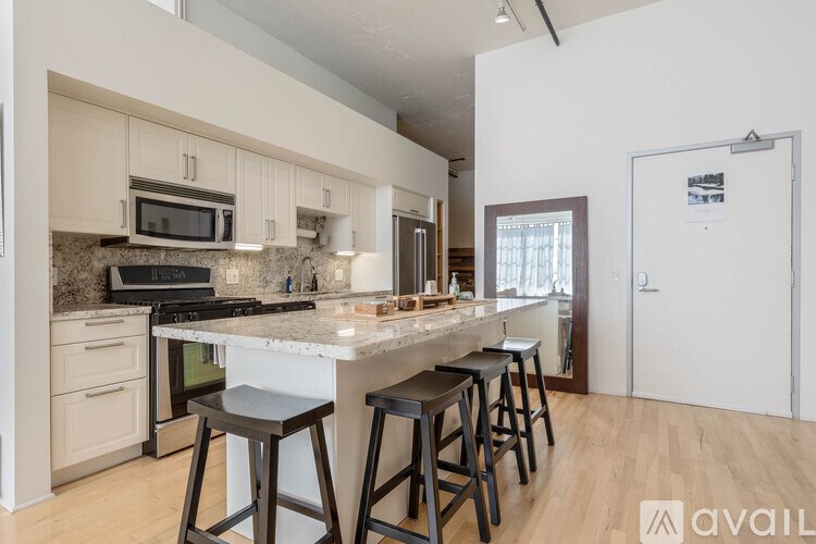 A kitchen with a white island and bar stools.