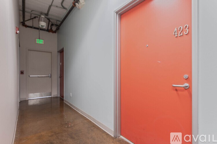 A hallway with a red door and a green exit sign.