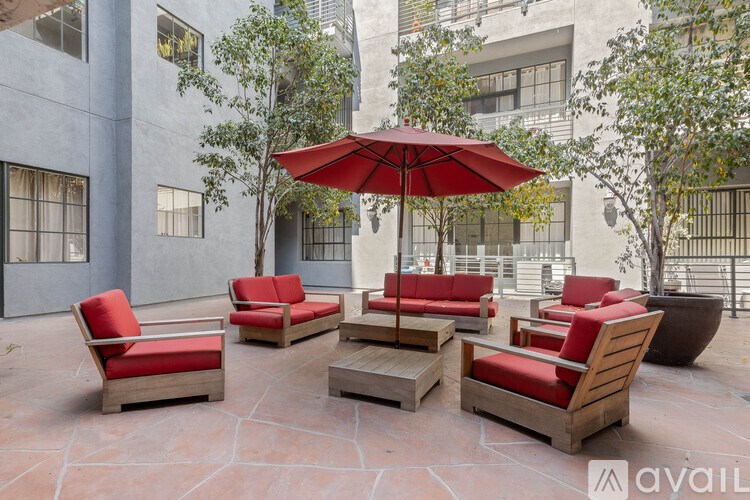 A patio with red chairs and a red umbrella.
