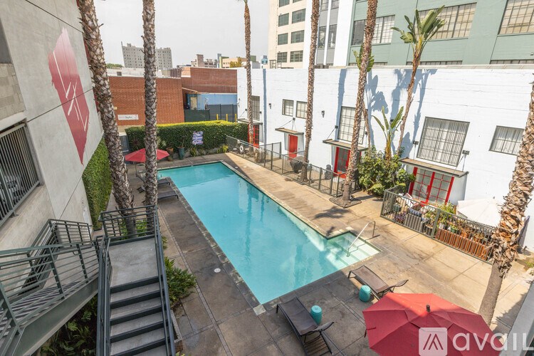 A pool surrounded by palm trees and a red umbrella.