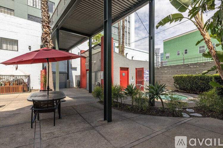 A patio with a table and chairs under a red umbrella.