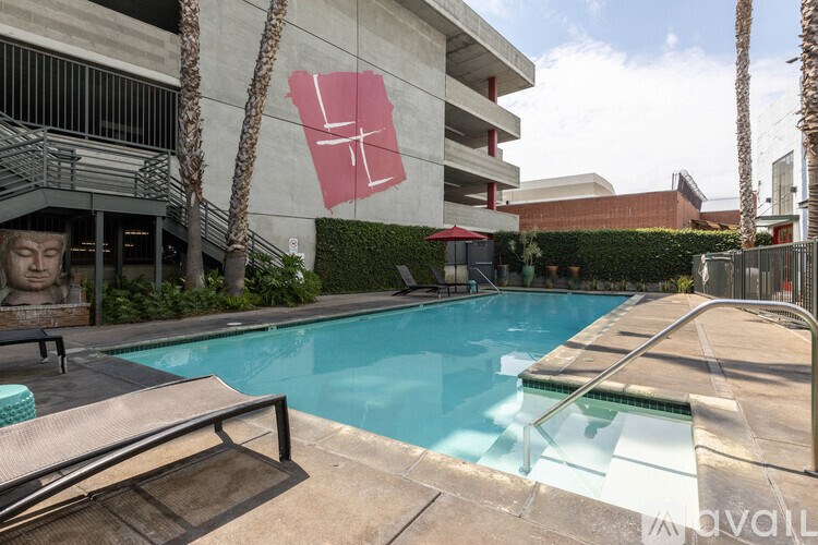 A pool with a red umbrella and a building with a red sign in the background.
