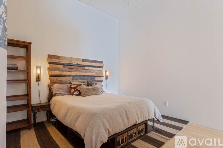 A bedroom with a bed, a wooden headboard, and a striped rug.