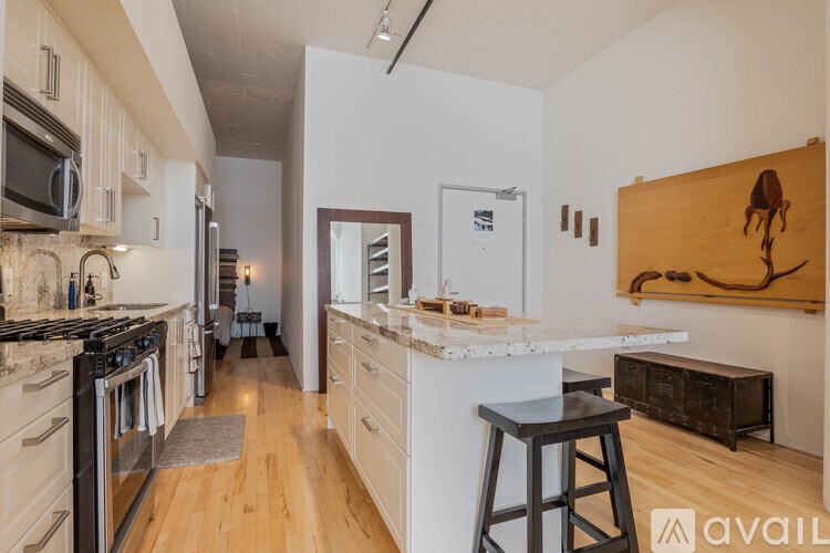 A kitchen with a white countertop and wooden floors.