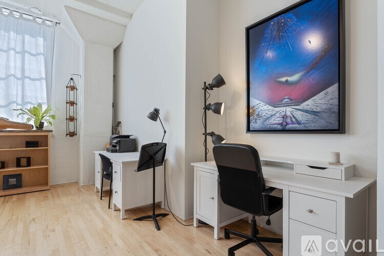 A room with a desk, chair, and a painting on the wall.