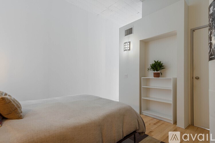 A bedroom with a bed, pillow, and a small plant on a shelf.