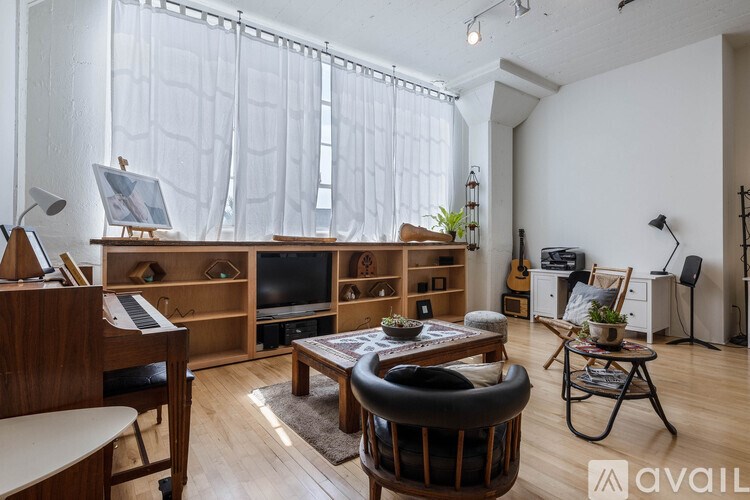 A living room with a piano, a chair, a table, and a bookshelf.