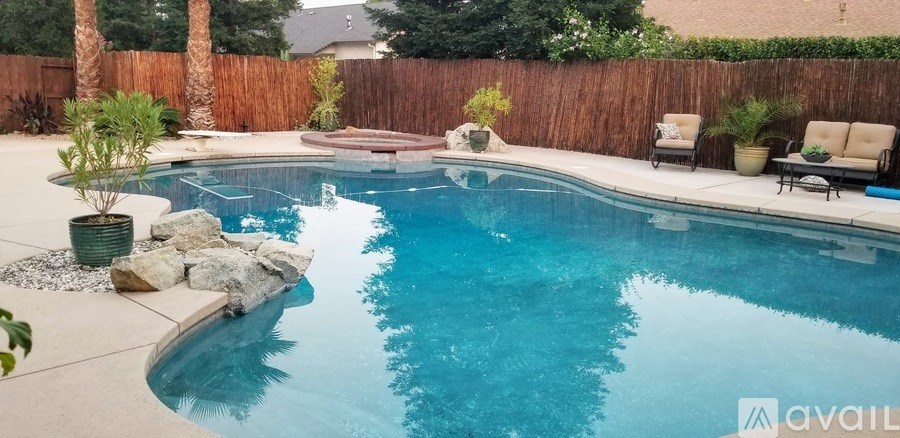 A pool with a waterfall and a rock in the middle.