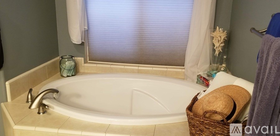 A bathroom with a tub and a window with blinds.