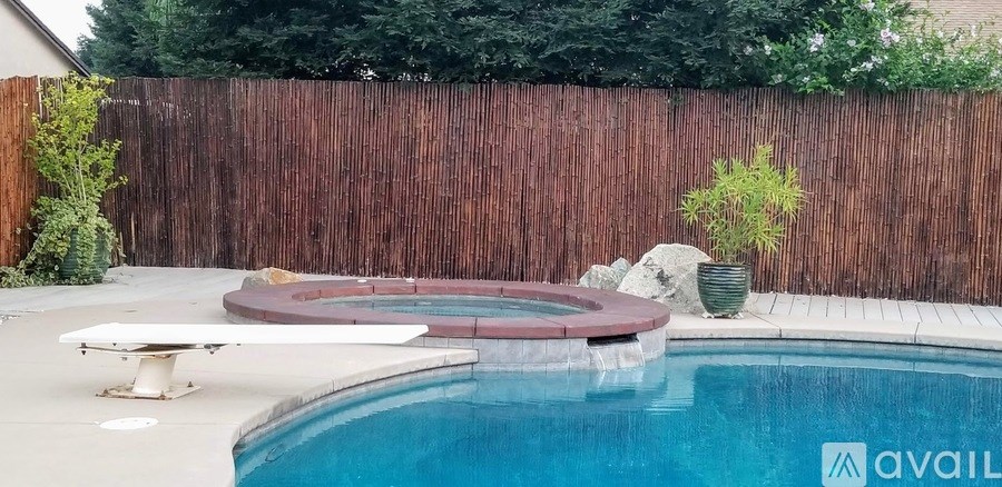 A pool with a bench and a fence.