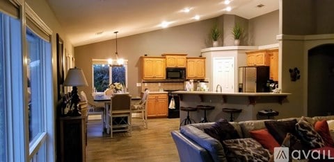 A well-lit living room with a kitchen in the background.