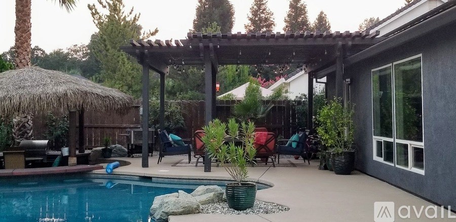 A pool with a thatched roof and a pergola.