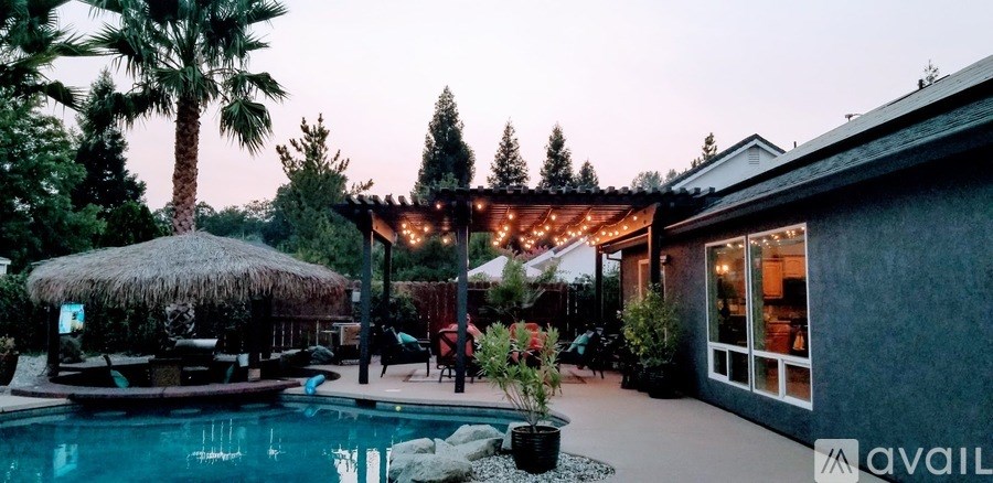 A pool surrounded by a thatched roof and palm trees.