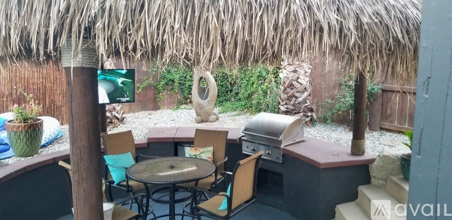 A patio with a table, chairs and a grill.