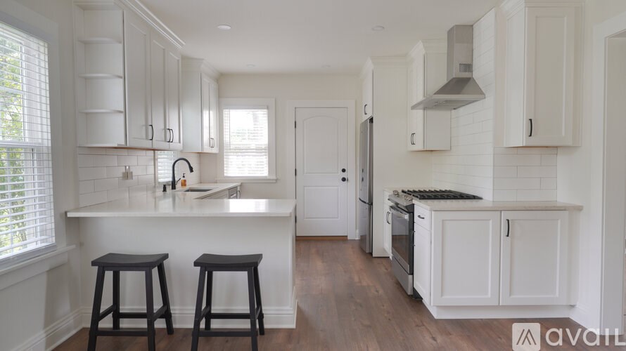 A kitchen with white cabinets and a wooden floor.