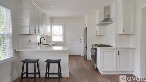 A kitchen with white cabinets and a wooden floor.