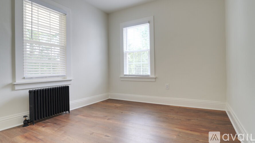 A room with wooden floors and two windows.